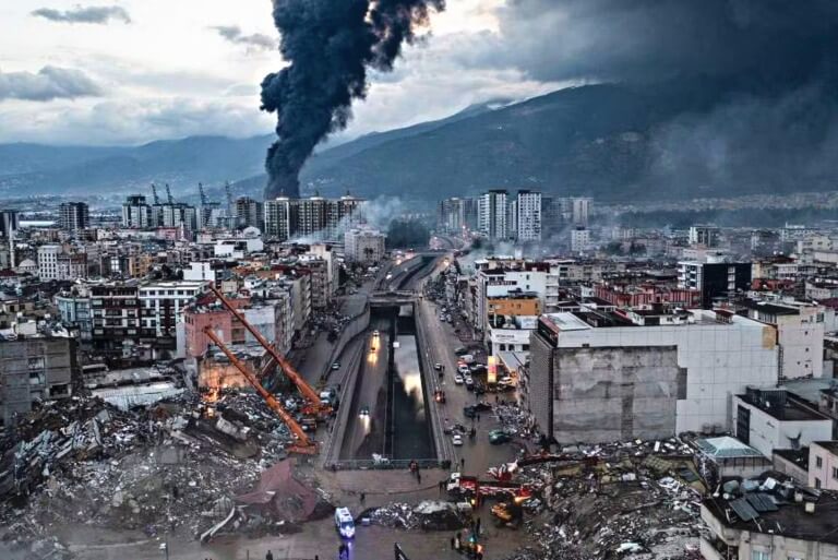 Urban disaster scene, smoke rising, damaged buildings, rescue efforts.