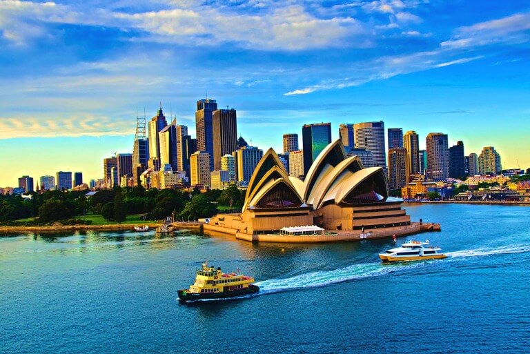 Sydney Opera House with city skyline and harbor ferries.
