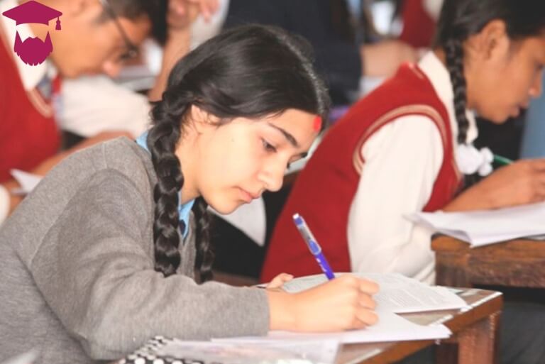 Student focused on writing in a classroom exam setting.