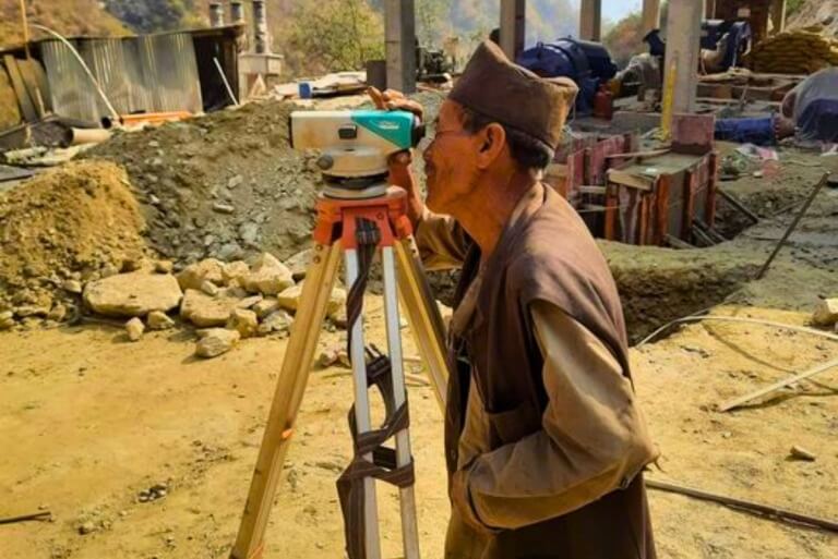 Surveyor using leveling instrument on construction site.