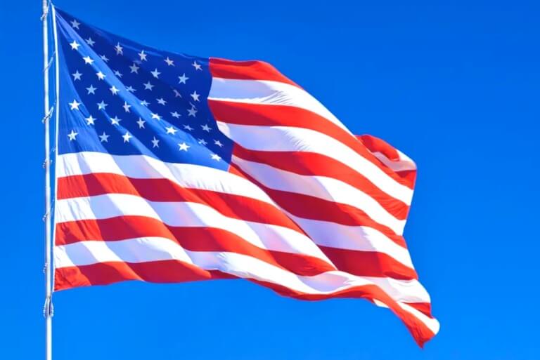 United States flag waving under clear blue sky.