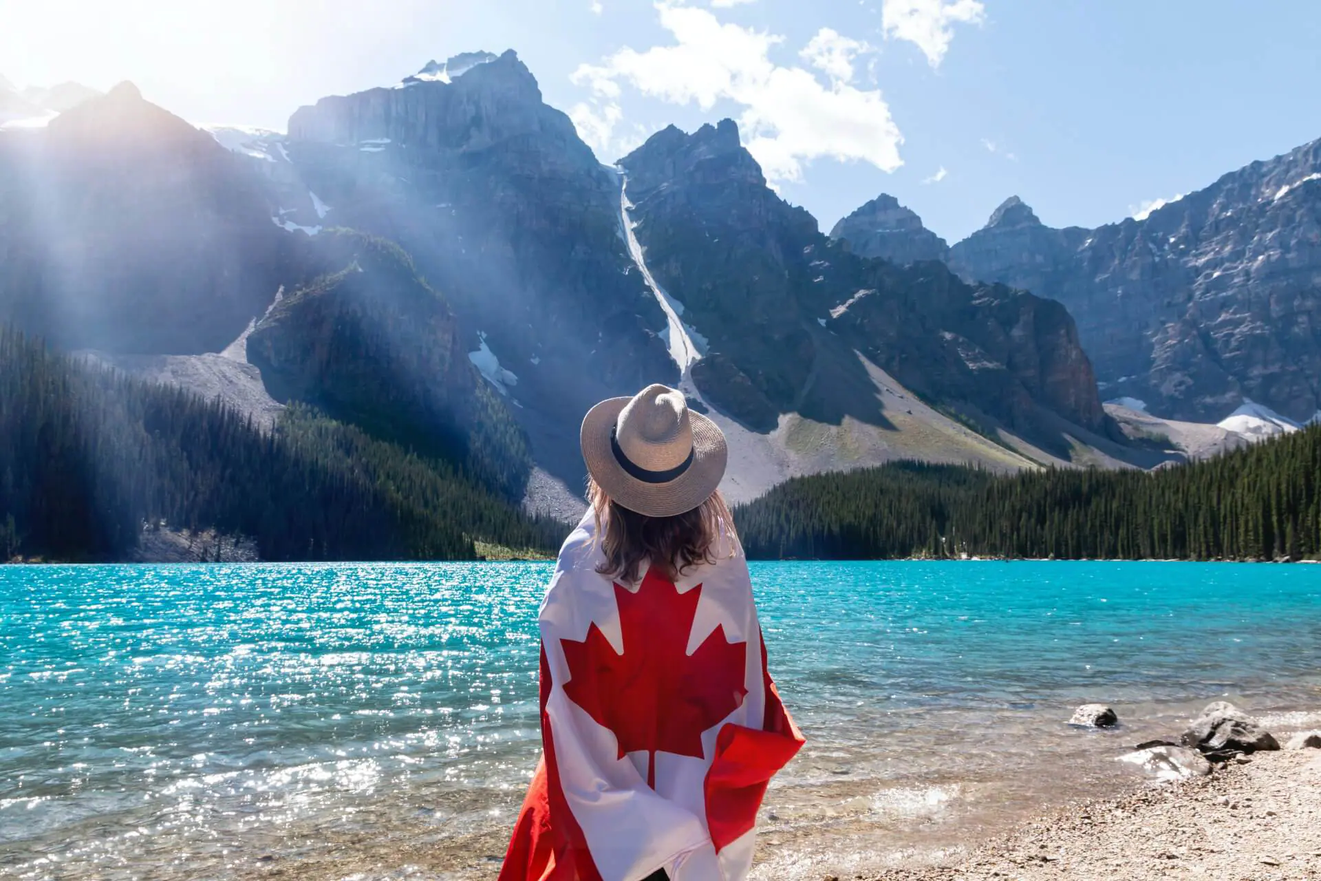 canada Person with Canadian flag at scenic mountain lake.