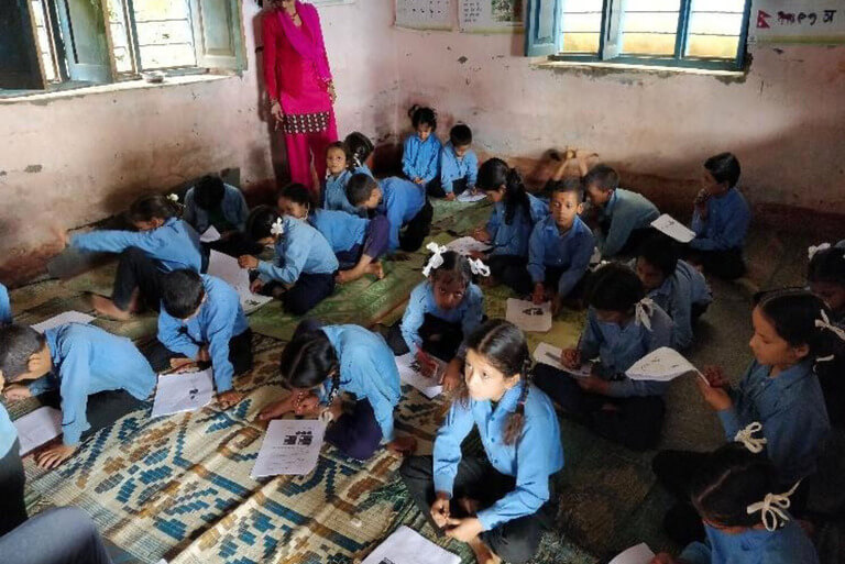Children studying in a classroom on mats.