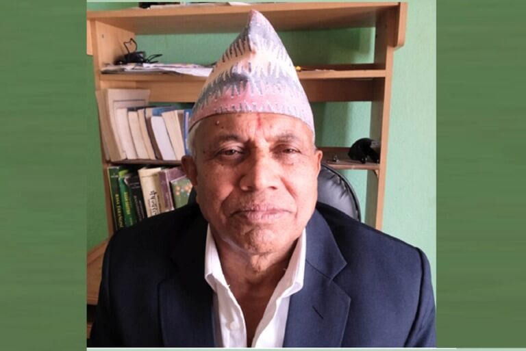 Man in traditional hat and suit with bookshelf background.