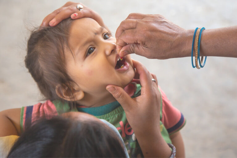Child receiving medication from adult caregivers.