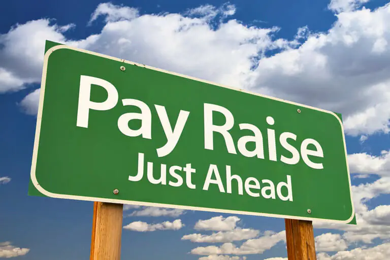 Green sign 'Pay Raise Just Ahead' against cloudy sky