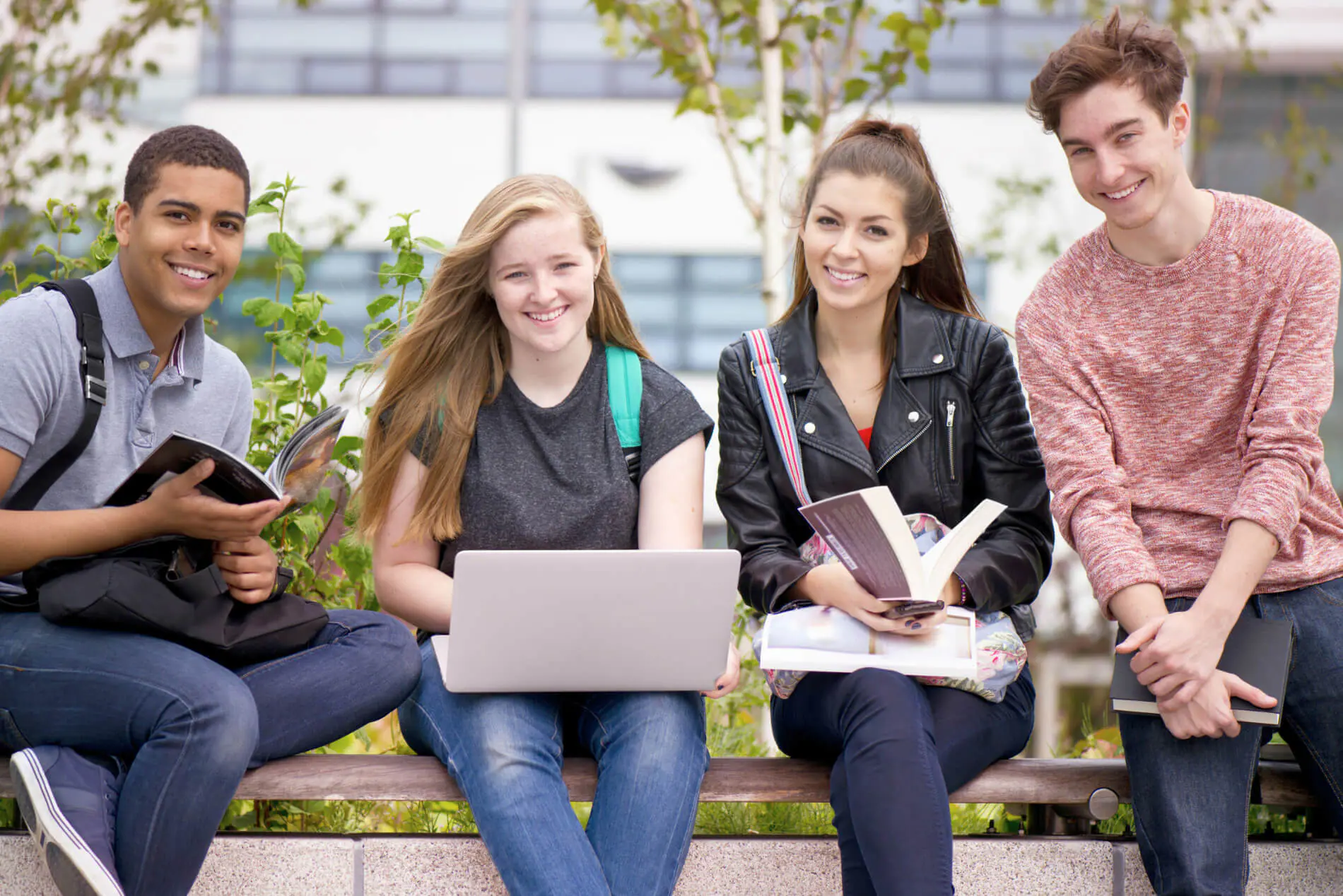 Students in UK Group of students studying outdoors with books and laptop.