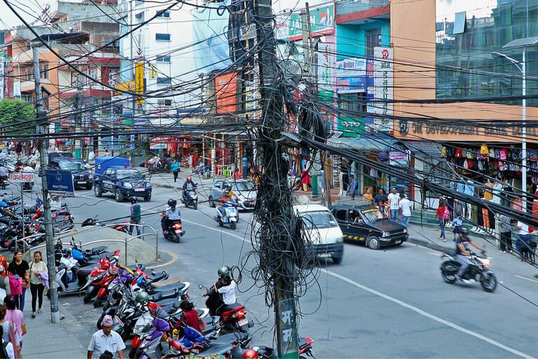 Bustling street in Kathmandu with tangled power lines.