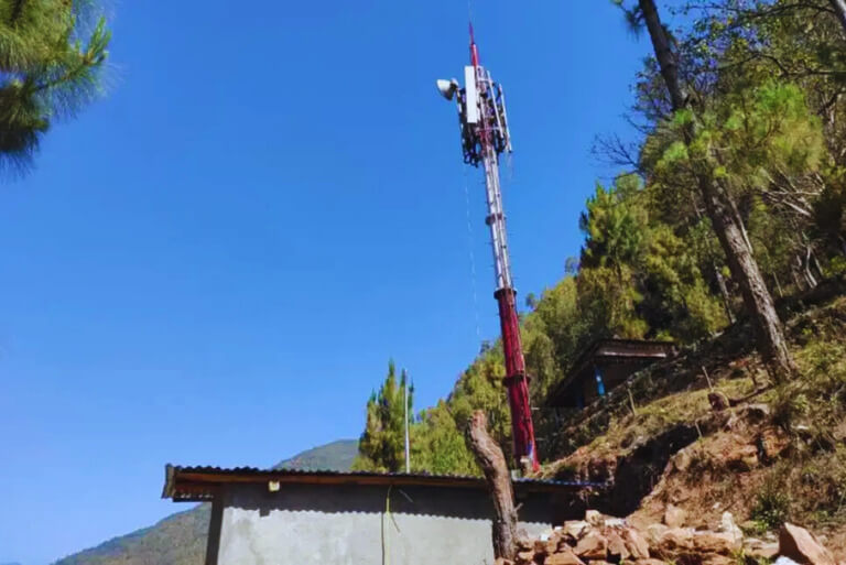 Telecom tower in forested hillside setting.
