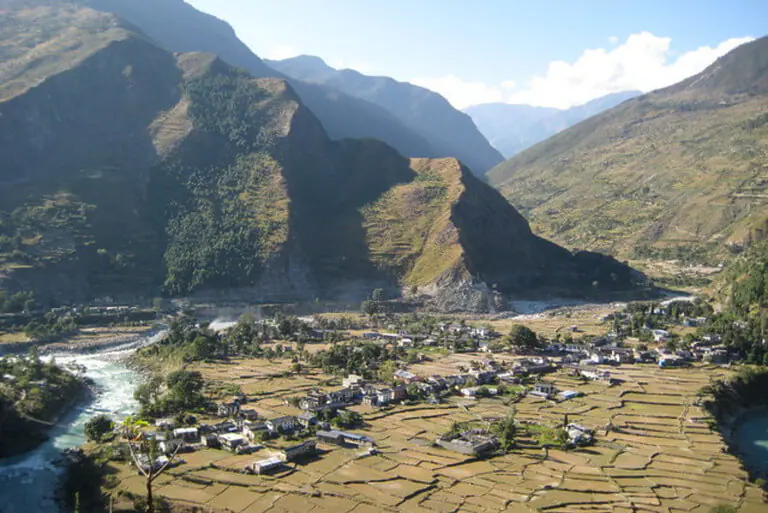 Scenic Himalayan village with terraced fields and mountains.