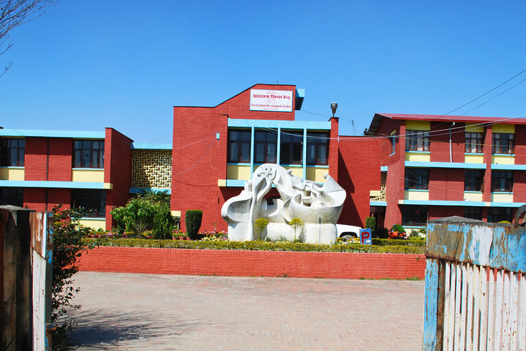 Red brick building with abstract statue outside.