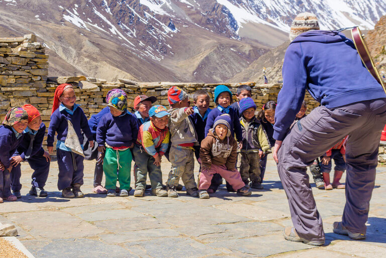 Kids laughing with a guide in a mountain village setting.