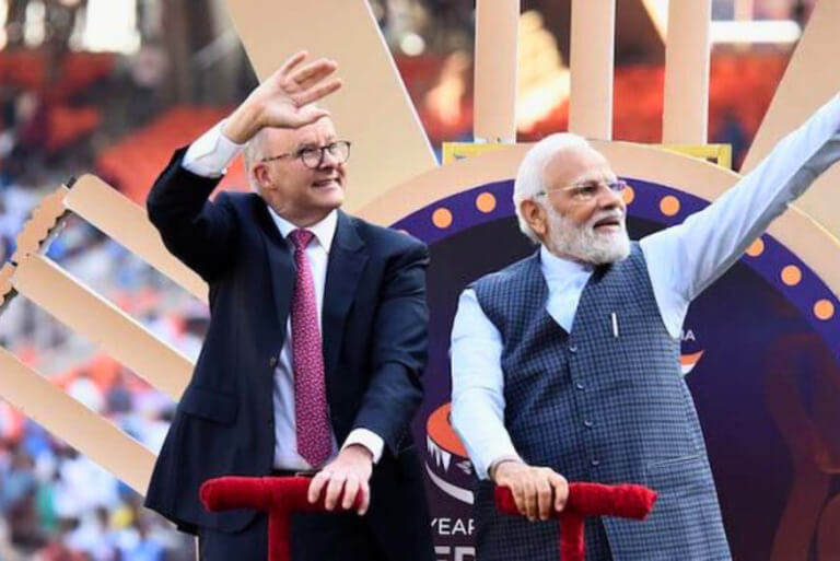 Two men waving at an outdoor event.