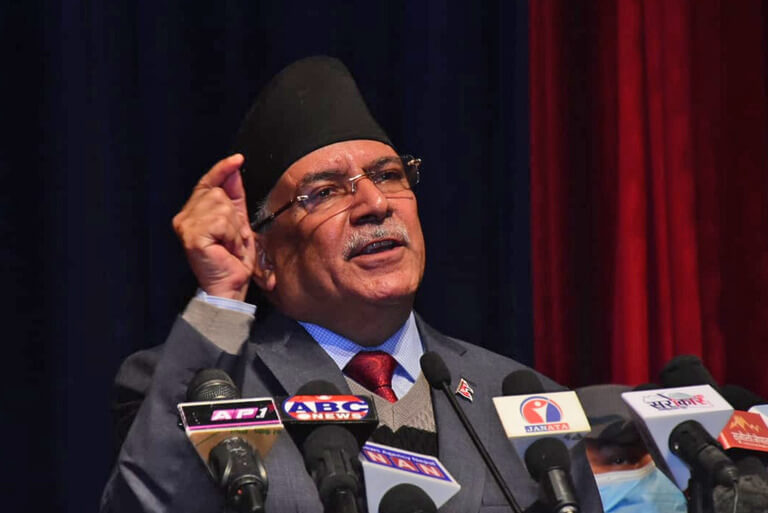 Man speaking at a press conference with multiple microphones.