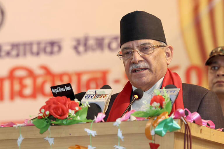 Man in traditional cap speaking at podium with microphones.