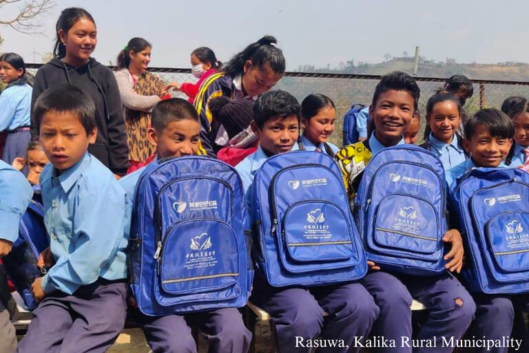 Smiling children with blue backpacks in school uniforms.