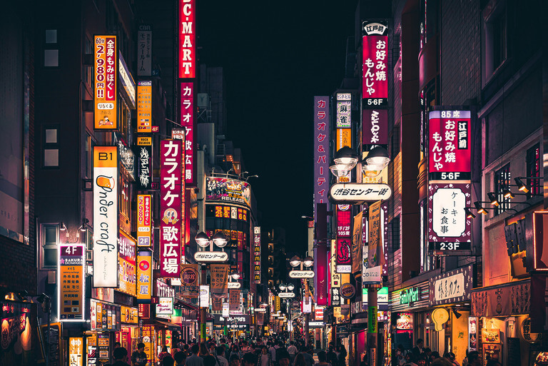 Bustling Tokyo street with vibrant neon signs at night.