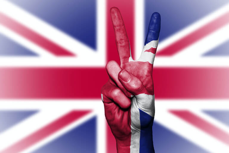 Hand making V-sign with Union Jack flag background.
