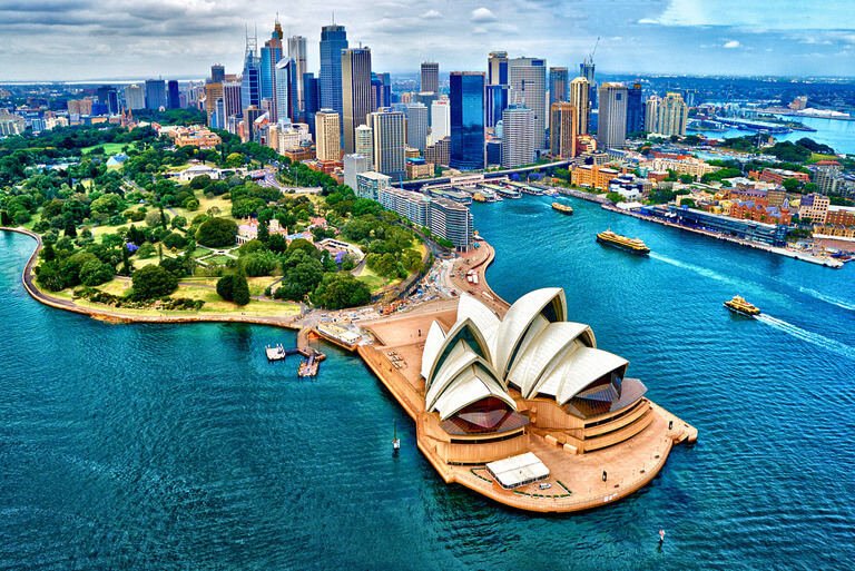 Sydney Opera House with city skyline and harbor view.