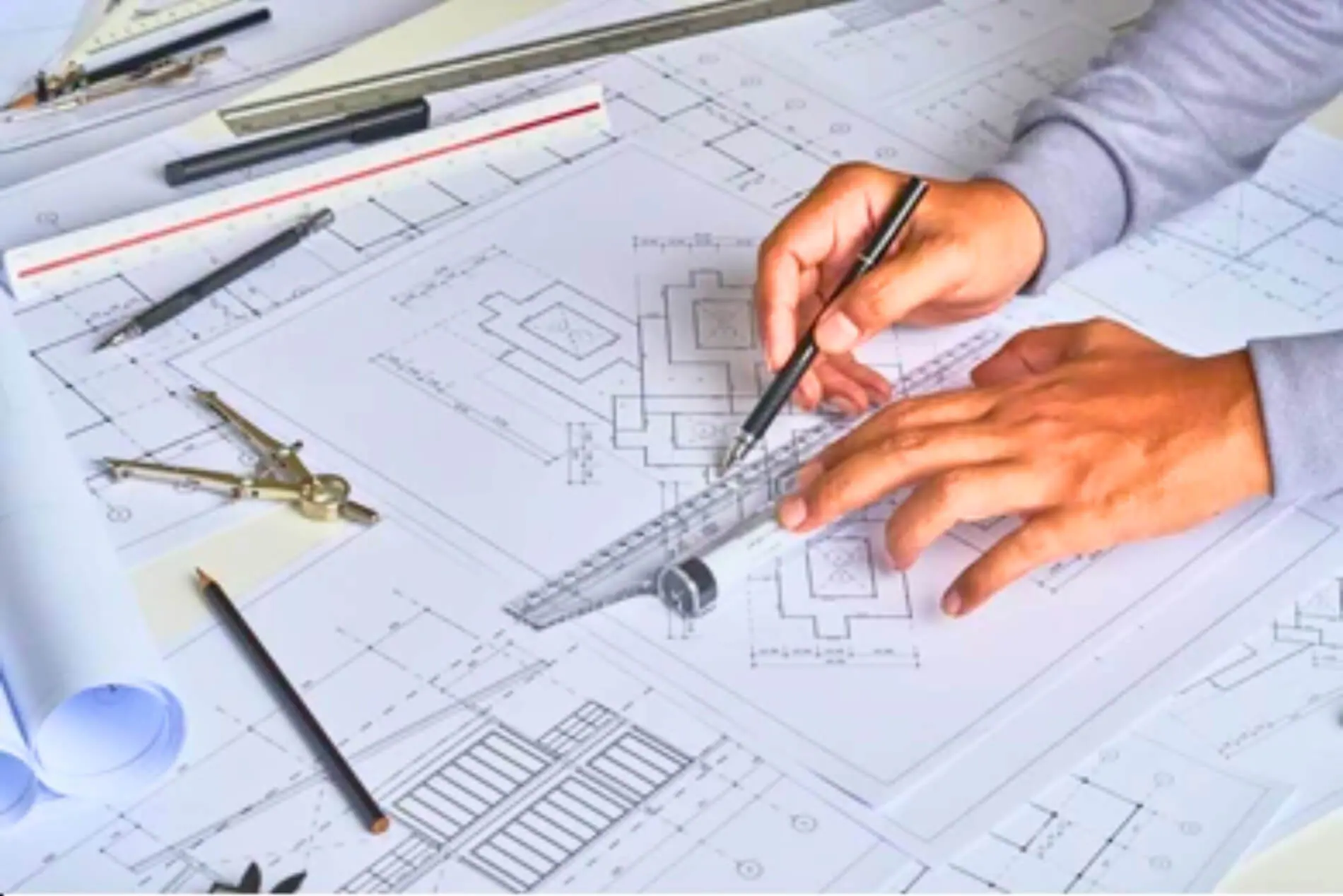 Architect drafting plans with compass and ruler.
