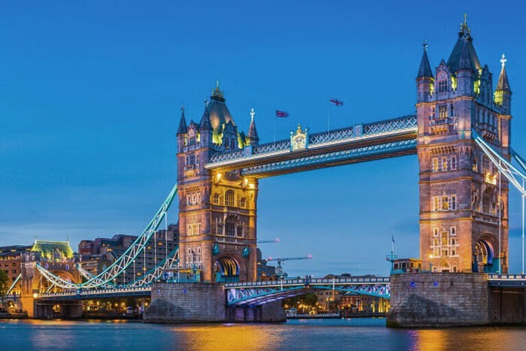 Tower Bridge illuminated at dusk over the Thames River.