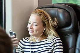 Woman enjoying music on train with earphones.
