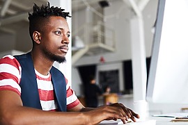 Man focusing on computer work in modern office space.