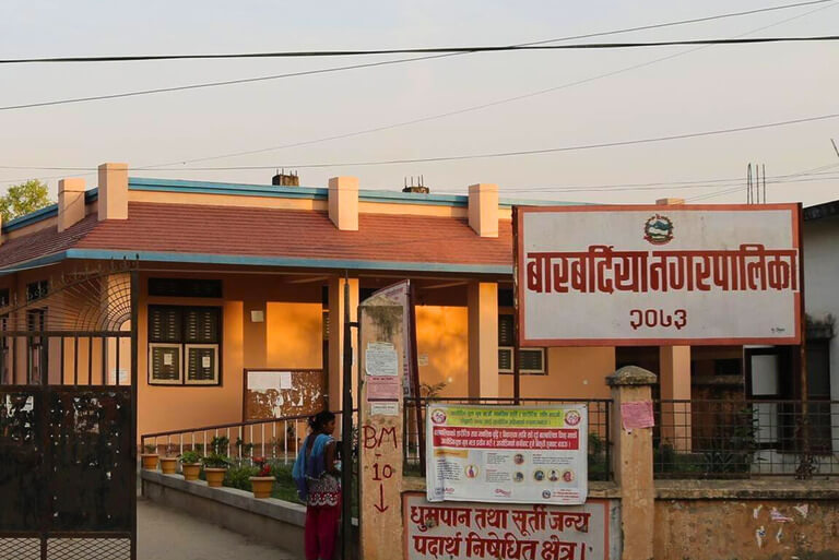 Municipal building entrance with signs and a person nearby.