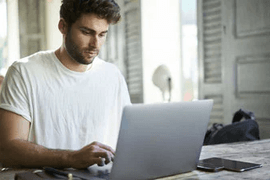 Man working on laptop in modern cafe setting.