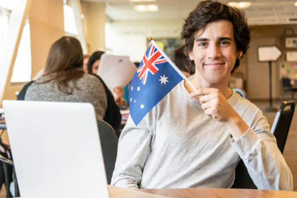 Smiling person with Australian flag in a classroom setting.