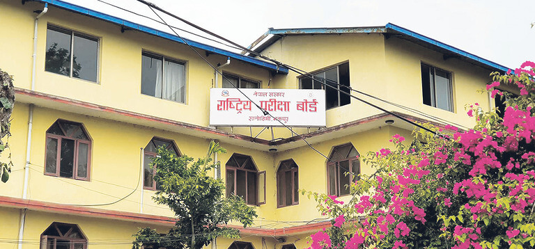 Yellow building with sign and pink flowers.