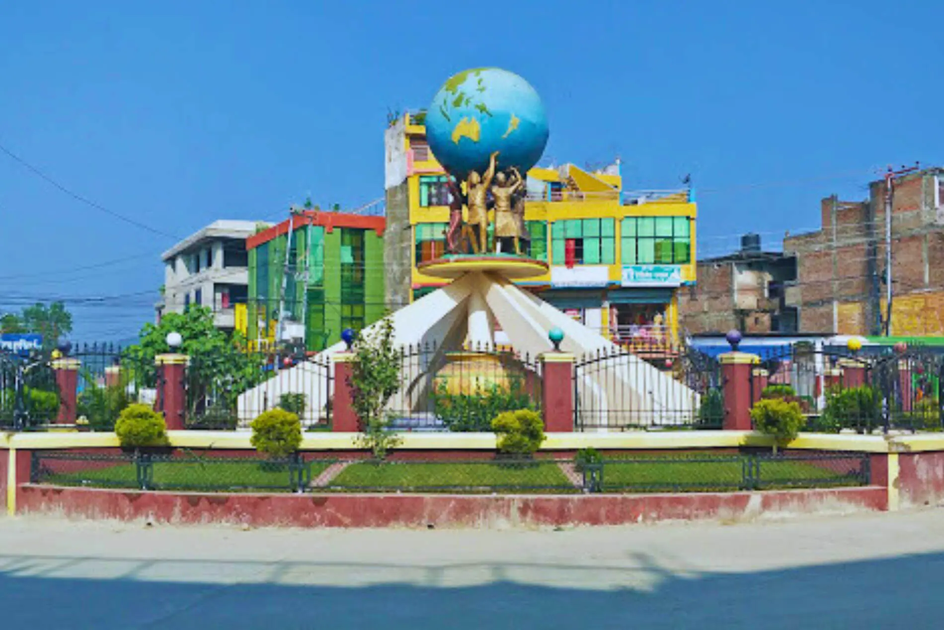 Colorful globe monument with statues in a vibrant urban setting.