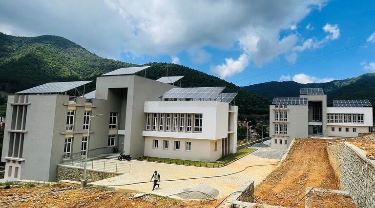 Modern buildings with solar panels in a hilly landscape.