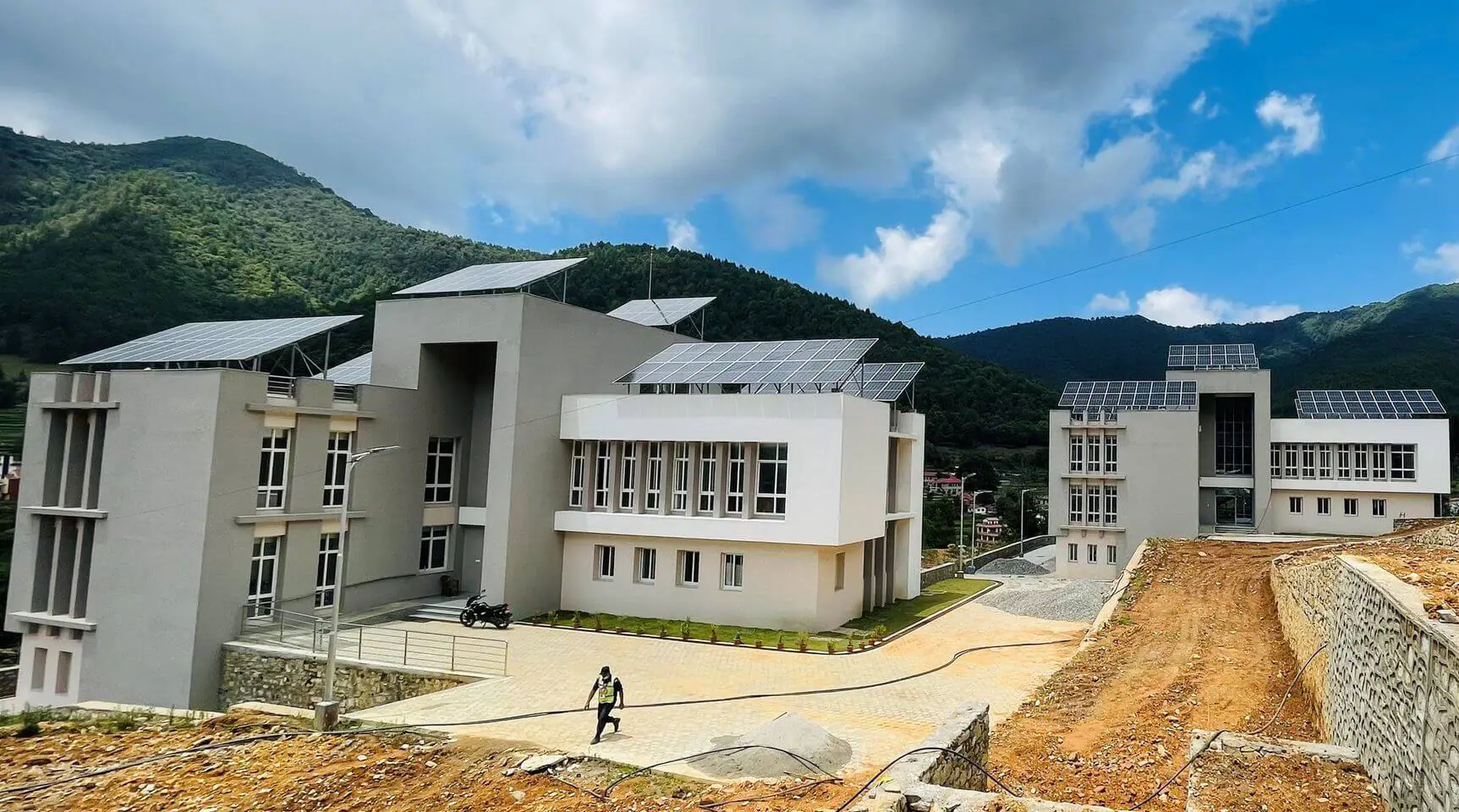 Madan-bhandari-University-of-Science-and-Technology Modern buildings with solar panels in a hilly landscape.
