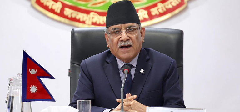 Man in suit speaking at a conference with Nepali flag.