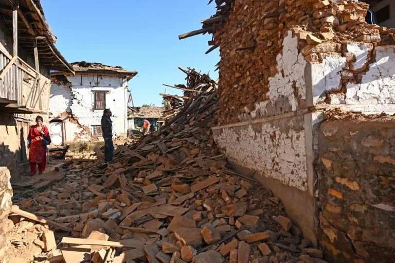 Earthquake damage with people walking among debris and collapsed buildings.