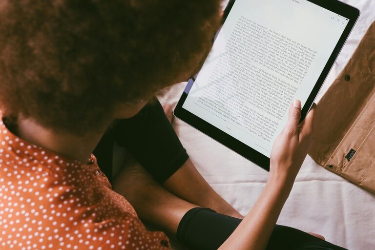 Person reading an ebook on a tablet indoors.