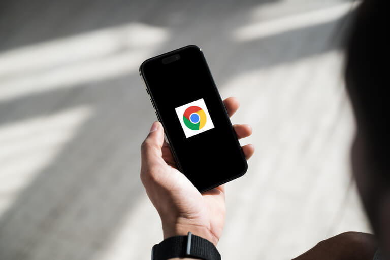 Hand holding smartphone with Chrome logo on screen.