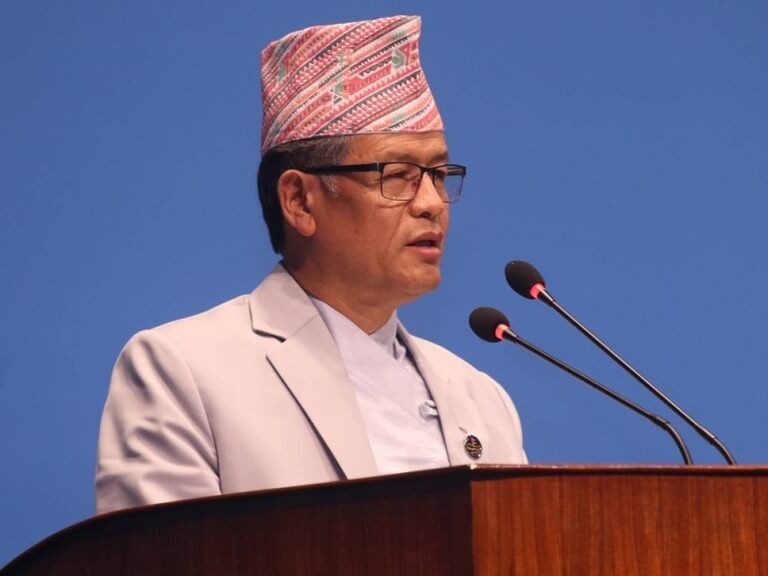 Man in traditional hat speaking at podium.