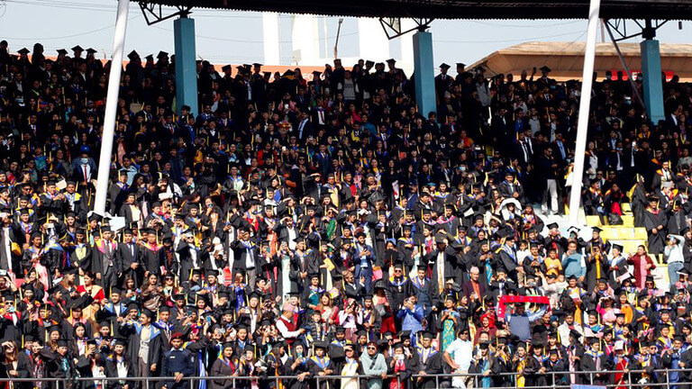 Large group of graduates in caps and gowns at ceremony.