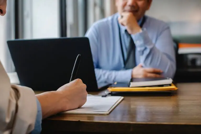 Job interview with laptop and notes in office setting.